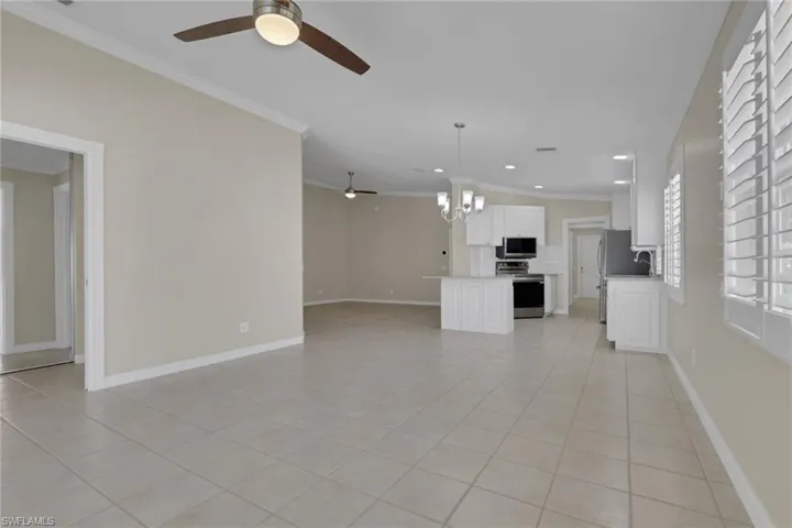 Open-concept living area with tile flooring, crown molding, and ceiling fans