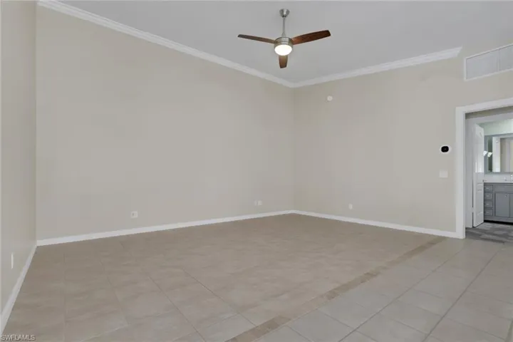 Ceramic tile flooring with decorative inlay, crown molding, and ceiling fan with integrated lighting
