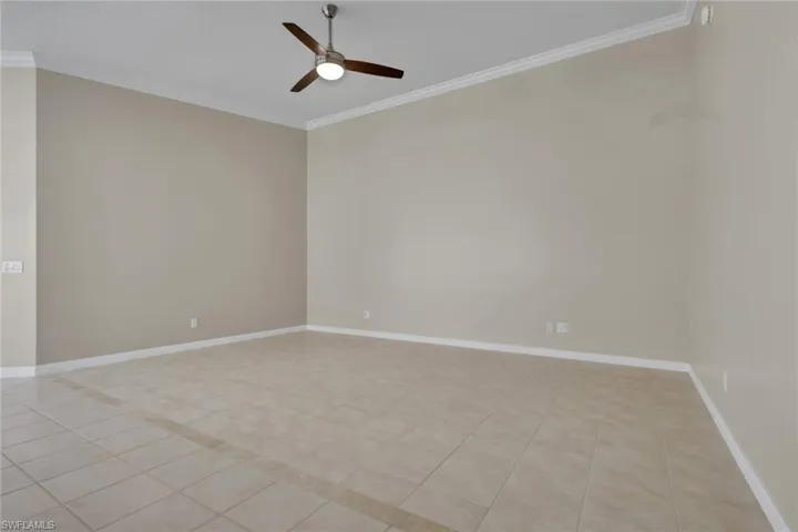 Spacious room featuring neutral-toned walls, crown molding, and tiled flooring with a decorative inlay