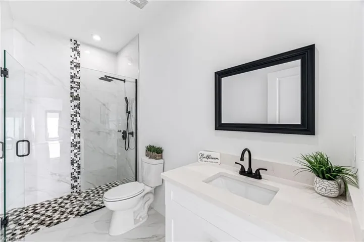 Bathroom featuring vanity, toilet, and a shower with shower door