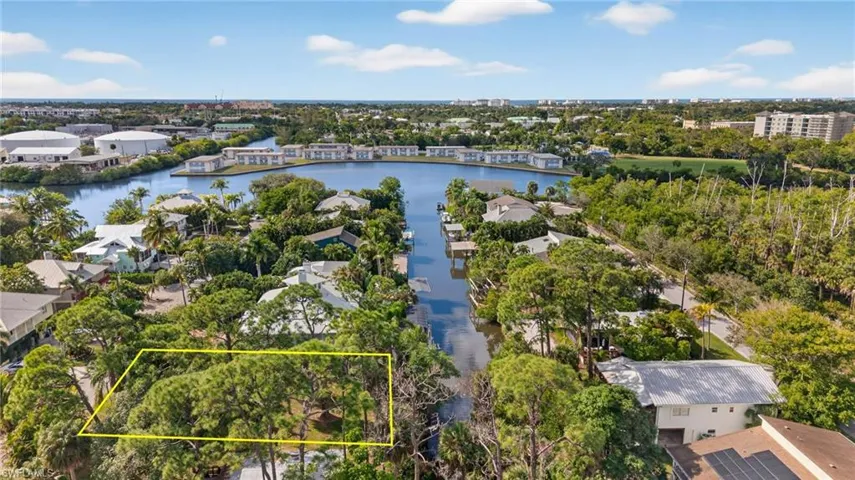Aerial perspective of suburban area featuring property parcel outlined and a nearby body of water