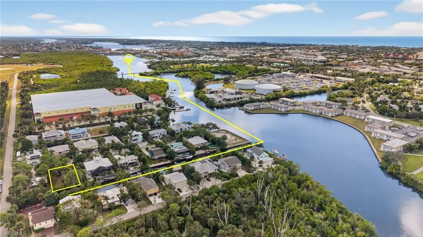 Aerial perspective of suburban area with property parcel outlined and a large body of water