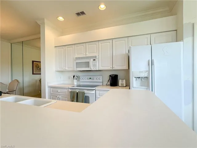 Kitchen featuring ornamental molding, sink, white appliances, and white cabinets