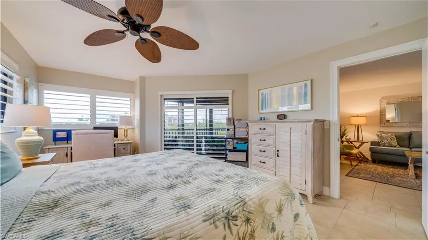 Ceiling fan with paddle blades, multiple windows with plantation shutters, sliding glass door, and a tiled floor