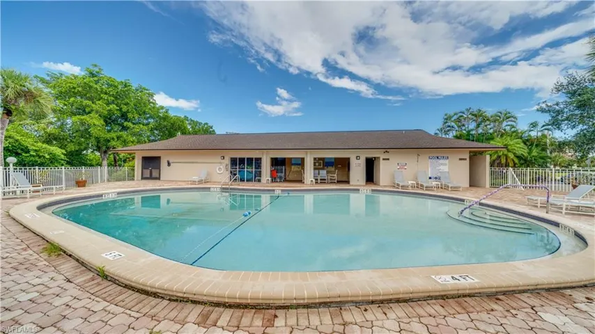 Outdoor swimming pool with integrated steps, brick paver decking, and a perimeter fence