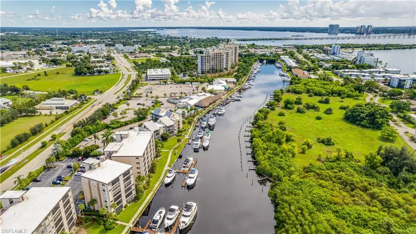 Waterfront canal with multiple boat slips, surrounded by lush green foliage and mature trees