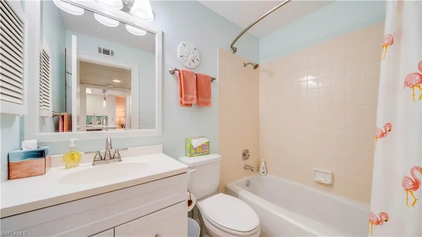 White vanity with integrated sink, chrome faucet, and rectangular mirror with mounted light fixture