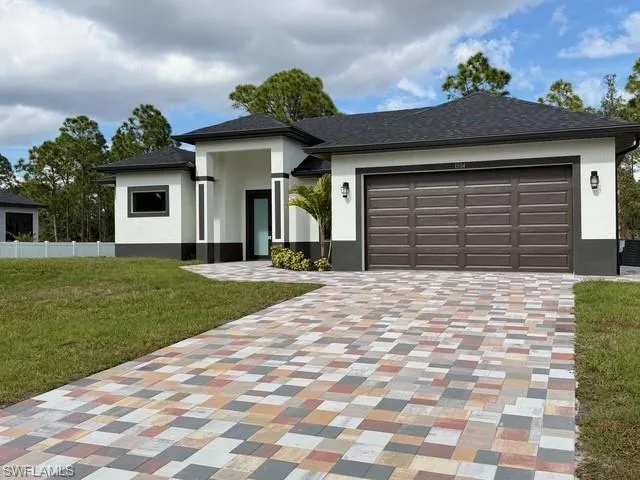 Prairie-style house with stucco siding, driveway, an attached garage, and roof with shingles
