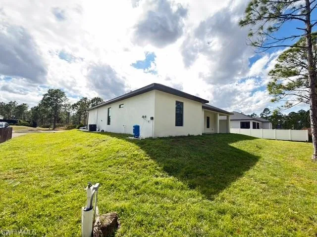 Rear view of house with a yard, stucco siding, and a patio