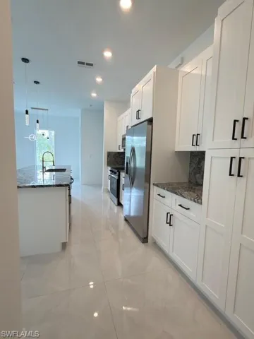Kitchen featuring stainless steel appliances, white cabinets, tasteful backsplash, dark stone counters, and recessed lighting