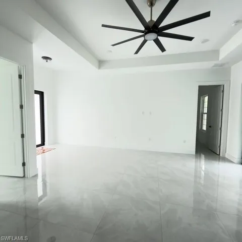 Unfurnished living room with a raised ceiling, ceiling fan, recessed lighting, and french doors
