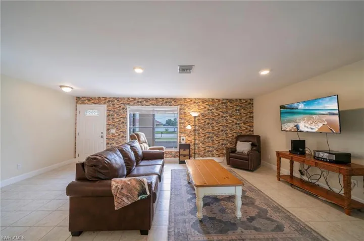 Living room featuring light tile patterned flooring, an accent wall, and recessed lighting
