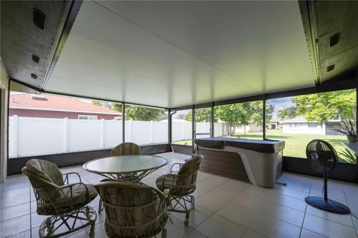 Sunroom / solarium featuring healthy amount of natural light, a hot tub, and outdoor dining space