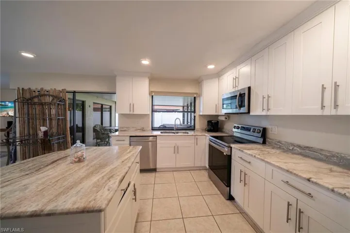 Kitchen with appliances with stainless steel finishes, light stone counters, light tile patterned floors, recessed lighting, and white cabinets