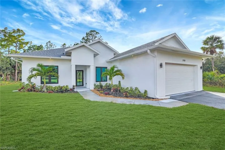 View of front of property featuring a garage and a front lawn
