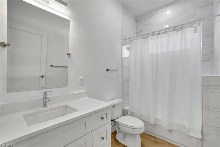 Full bathroom featuring vanity, toilet, wood-type flooring, and shower / tub combo