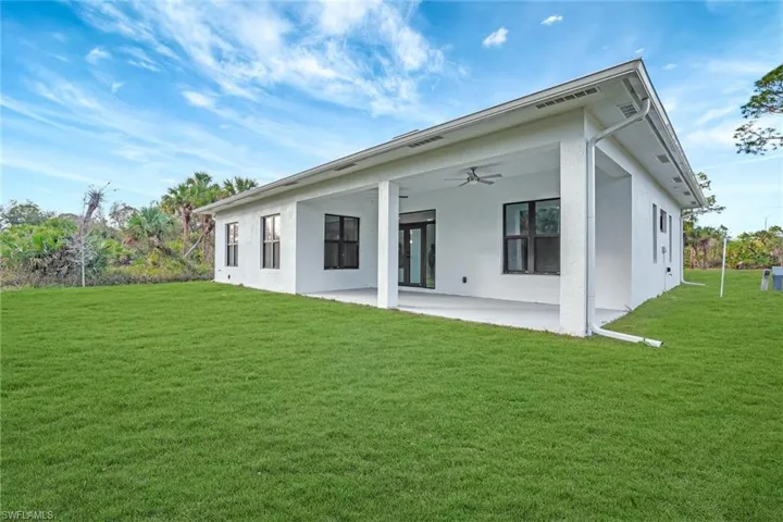 Back of property with ceiling fan, a yard, and a patio