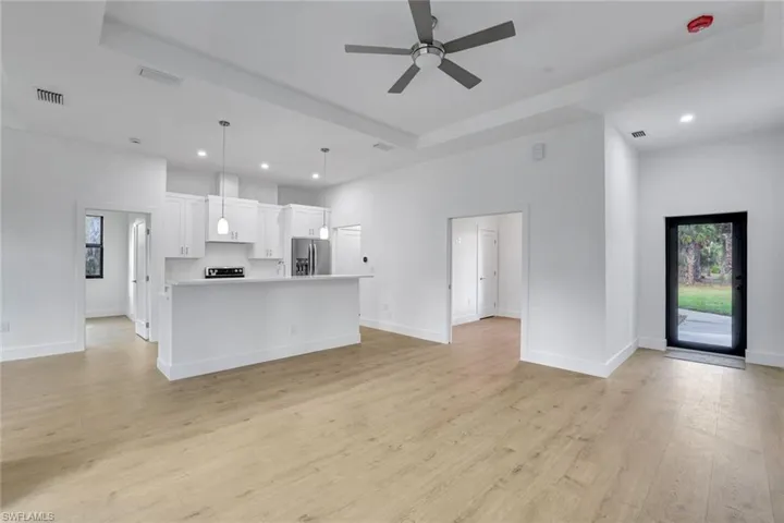 Kitchen with a kitchen island, light hardwood / wood-style flooring, stainless steel fridge, pendant lighting, and white cabinets