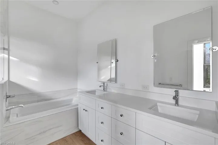 Bathroom with hardwood / wood-style floors, vanity, and a relaxing tiled tub