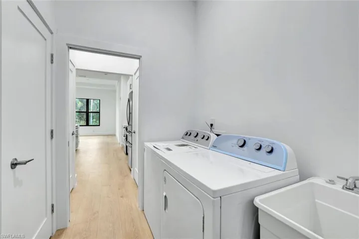 Laundry room featuring washer and dryer, light wood-type flooring, and sink