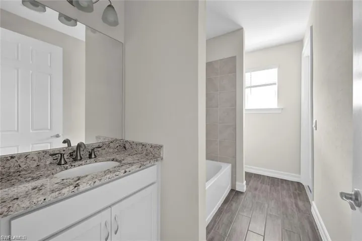 Full bath with vanity, wood tiled floors, and shower / washtub combination