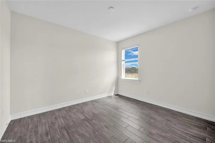 Empty room featuring baseboards and dark wood-style flooring