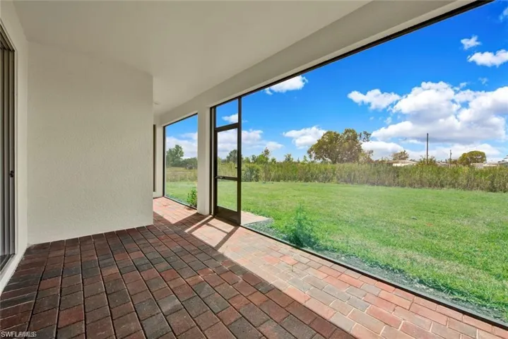 Unfurnished sunroom with brick flooring and a textured wall