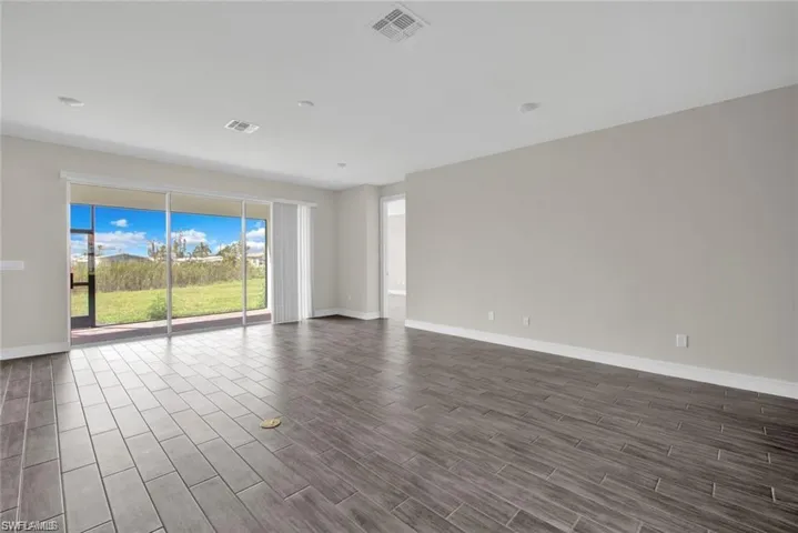 Empty room featuring baseboards and dark wood-type flooring