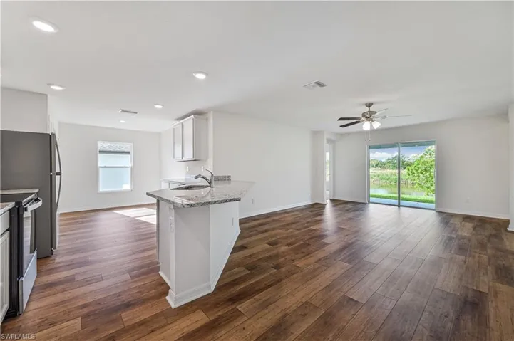 Kitchen with white cabinetry, a wealth of natural light, dark hardwood / wood-style flooring, light stone counters, and stainless steel electric range oven