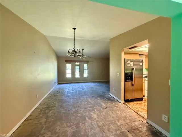 Unfurnished dining area featuring vaulted ceiling, baseboards, a chandelier, and visible vents