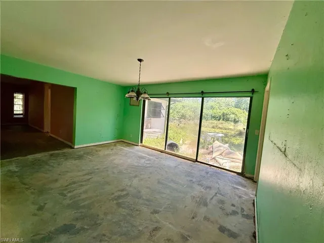 Unfurnished dining area with a chandelier, baseboards, and concrete flooring