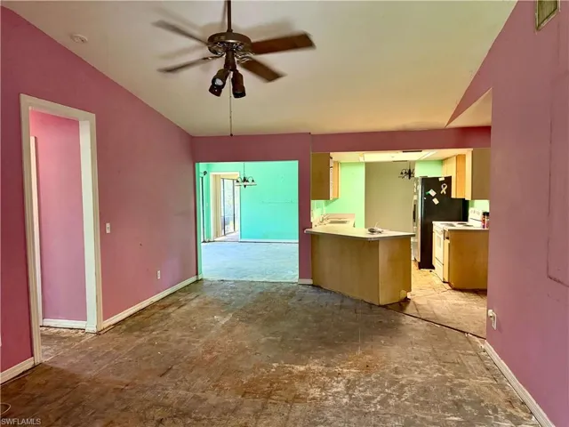 Kitchen featuring white electric stove, baseboards, lofted ceiling, ceiling fan, and light countertops