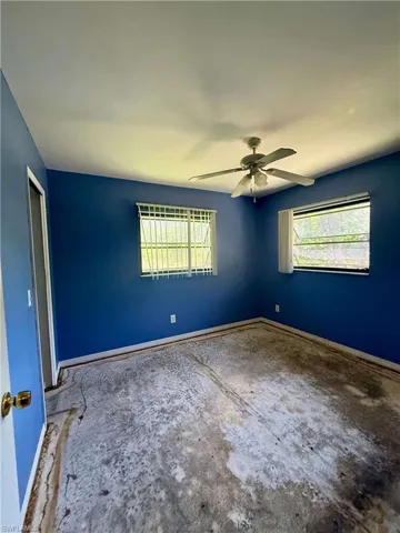 Bedroom room featuring unfinished concrete floors, ceiling fan, baseboards, and a healthy amount of sunlight