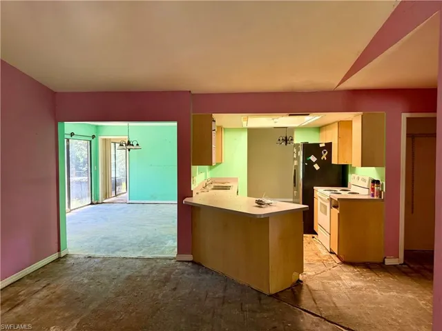 Kitchen with electric stove, a chandelier, baseboards, light countertops, and a peninsula