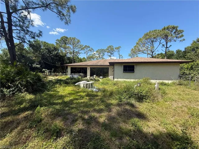 Rear view of house with stucco siding and fence
