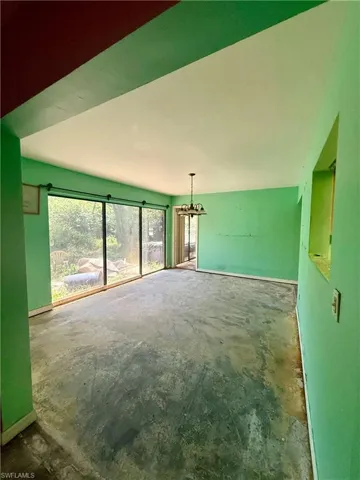 Spare room with baseboards, an inviting chandelier, and unfinished concrete flooring