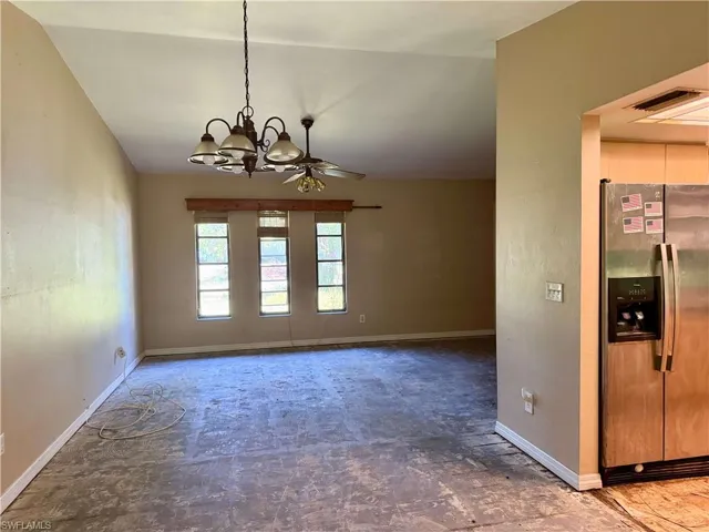 Unfurnished dining area featuring visible vents, baseboards, and ceiling fan with notable chandelier