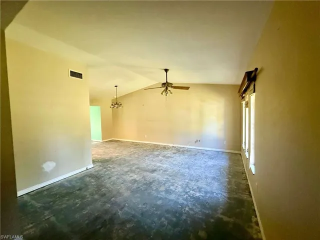 Empty room with concrete floors, ceiling fan, baseboards, lofted ceiling, and visible vents