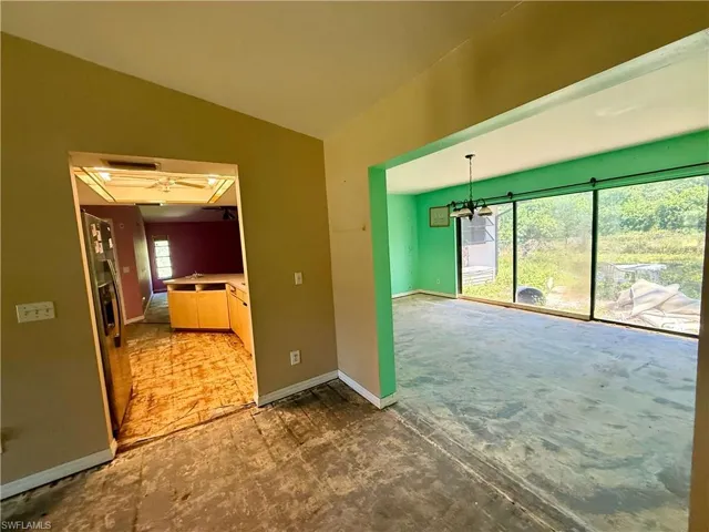 Spare room with lofted ceiling, baseboards, and a notable chandelier
