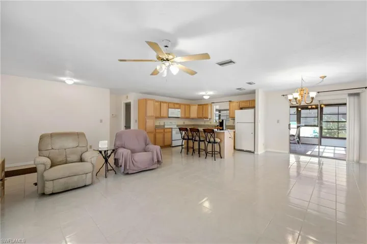Living room with ceiling fan with notable chandelier and light tile floors