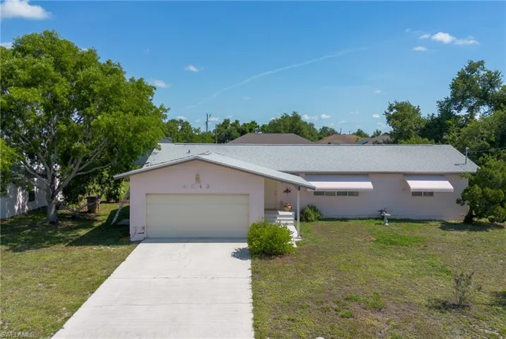Single story home with a garage and a front lawn