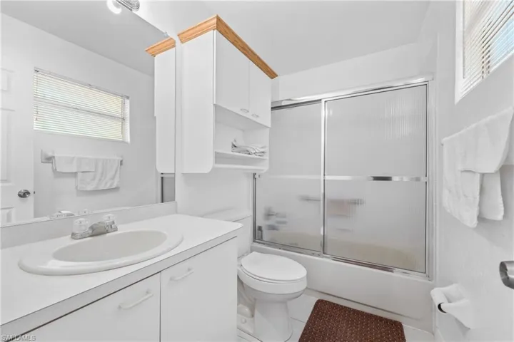 Full bathroom with shower / bath combination with glass door, tile flooring, toilet, and large vanity