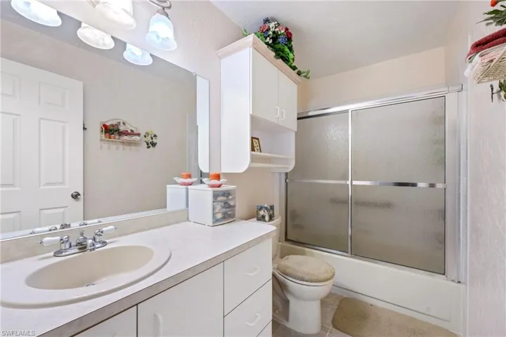 Full bathroom featuring tile flooring, combined bath / shower with glass door, vanity, and toilet