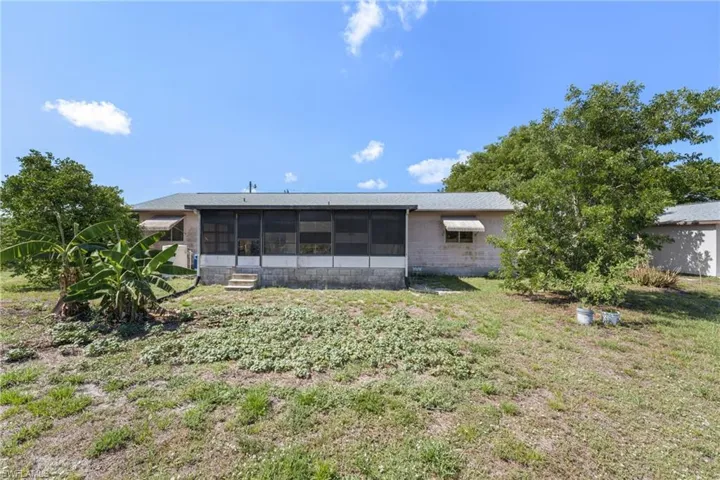 Rear view of property featuring a sunroom and a lawn