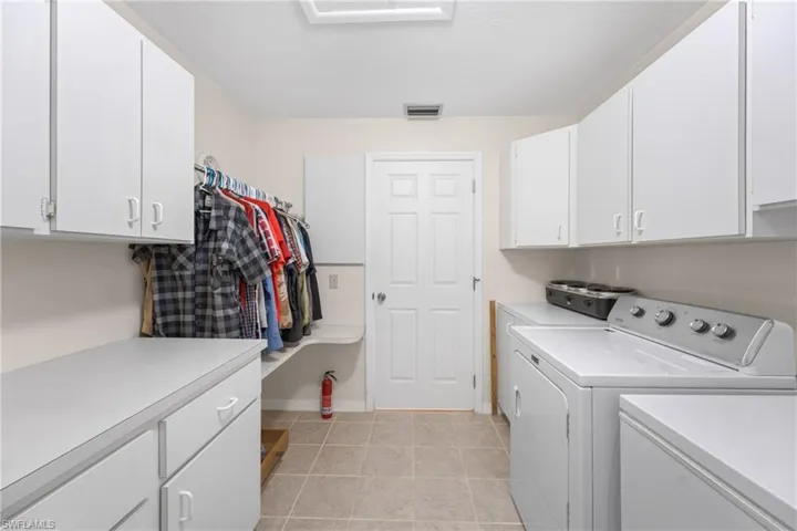 Laundry area featuring washer and clothes dryer, cabinets, and light tile flooring