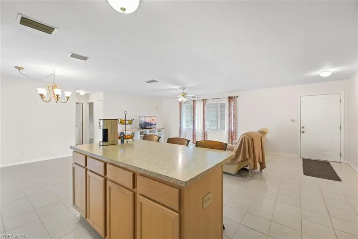 Kitchen featuring decorative light fixtures, a center island, light tile flooring, and ceiling fan with notable chandelier