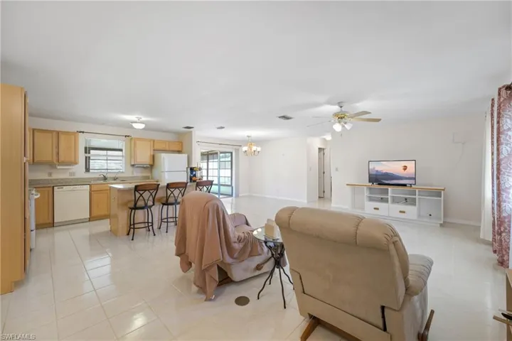 Living room featuring sink, light tile floors, and ceiling fan with notable chandelier