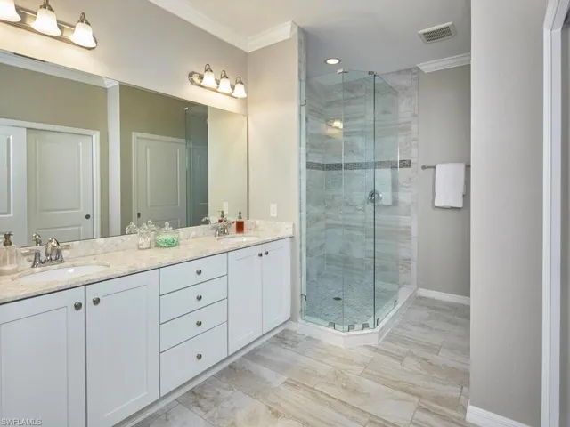The primary suite features a double vanity with plenty of counter and cabinet space, as well as a frameless walk-in shower with glass and floor to ceiling tile.