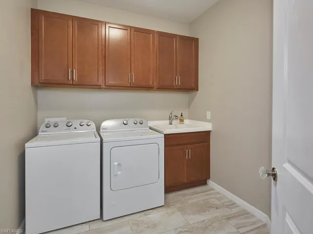 The aptly sized laundry room features a sink and plenty of cabinet space to store cleaning materials for life's little messes.