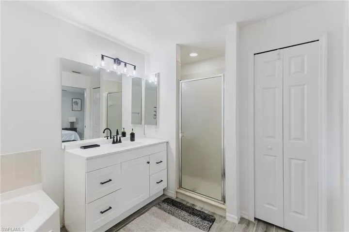 Ensuite bathroom featuring a closet, a stall shower, vanity, and a bath